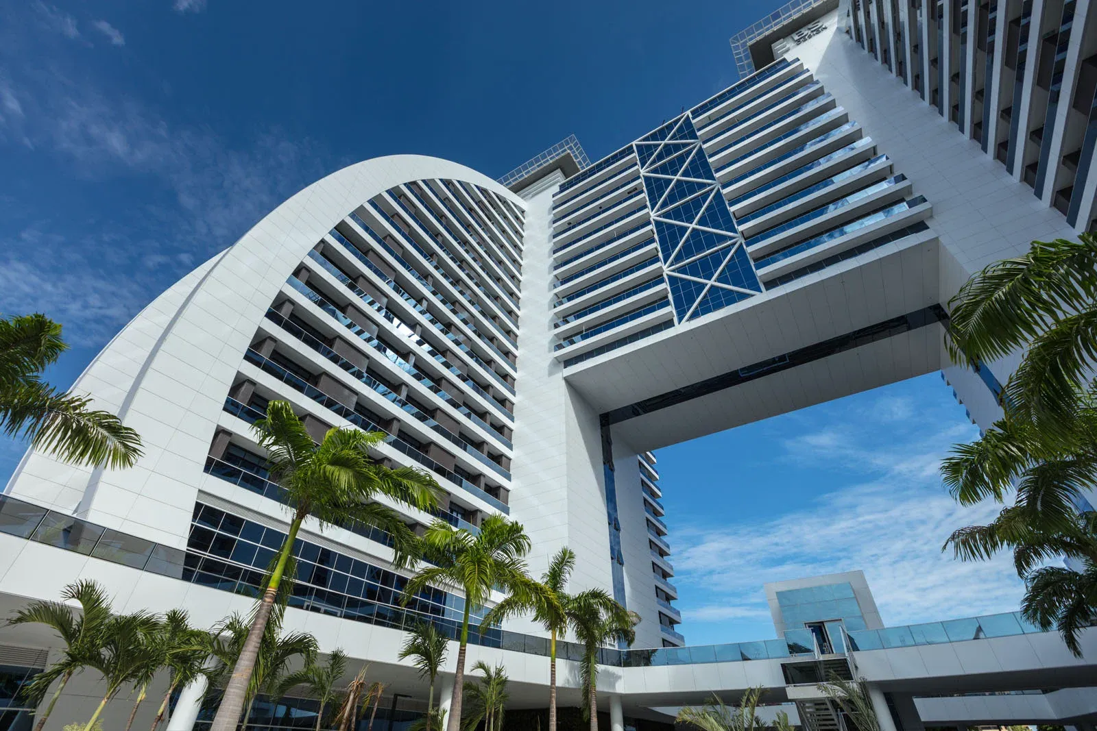 Edifício BS Design visto de baixo, com arco branco e palmeiras