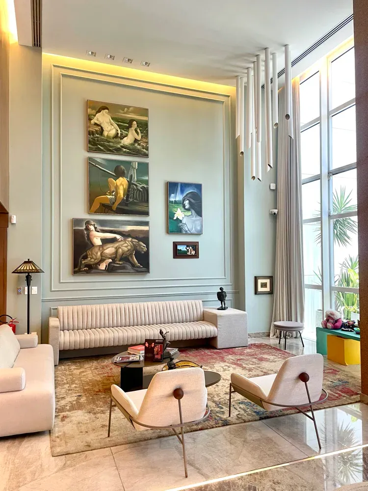 Lounge de pé-direito duplo da Clínica Jório Conceito, com obras de arte e sofás claros