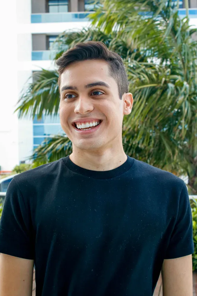 Paciente sorrindo ao ar livre entre palmeiras