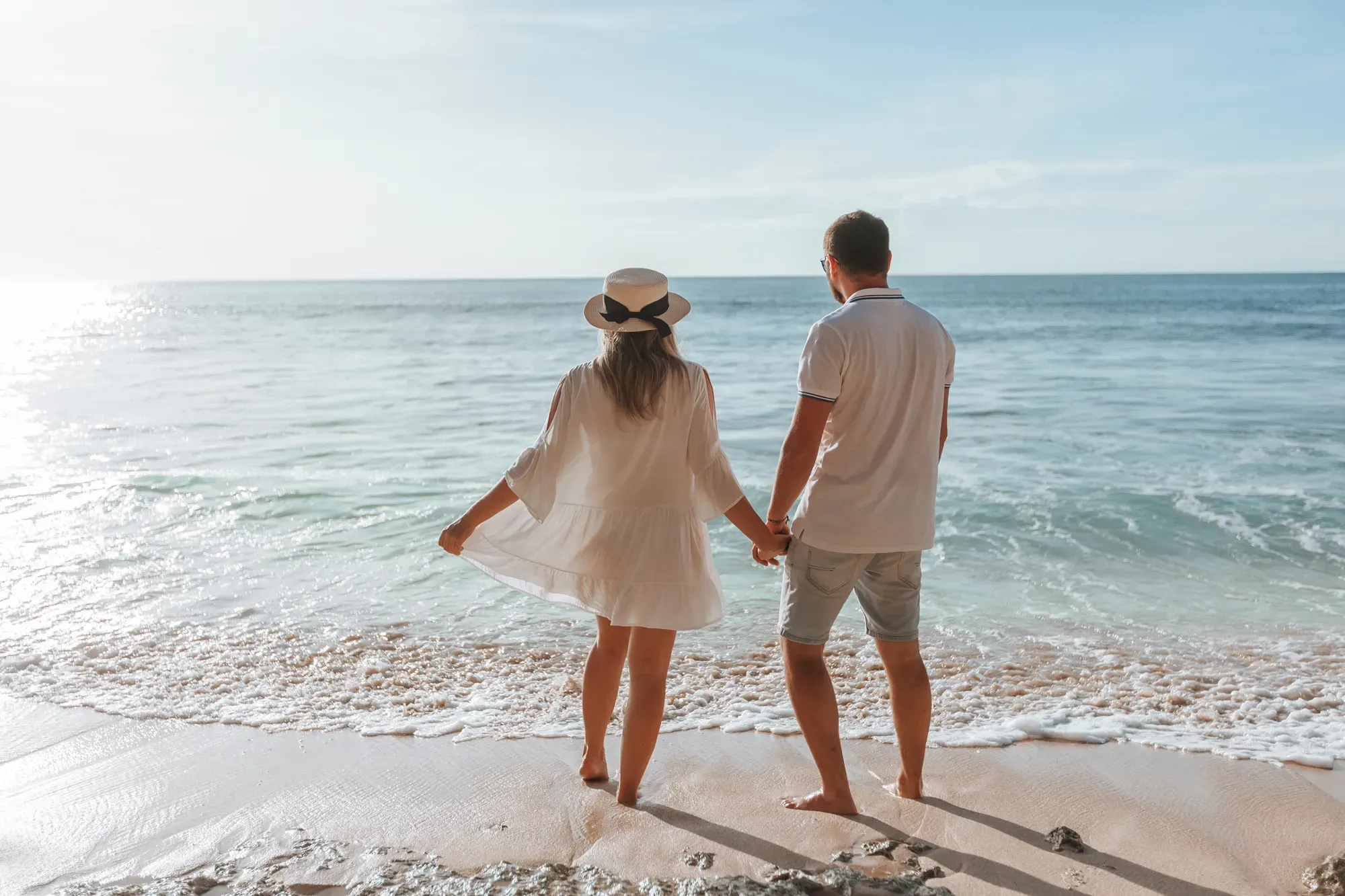 Casal de mãos dadas assistindo ao pôr do sol na praia