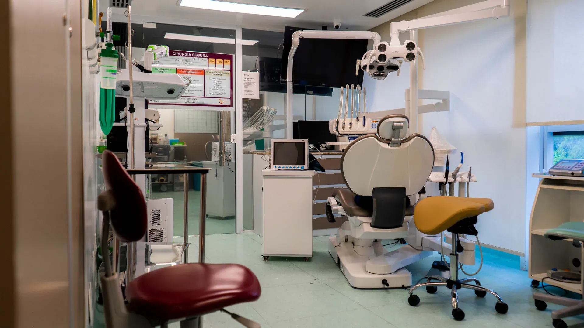 Sala de cirurgia com cadeira, microscópio e monitores